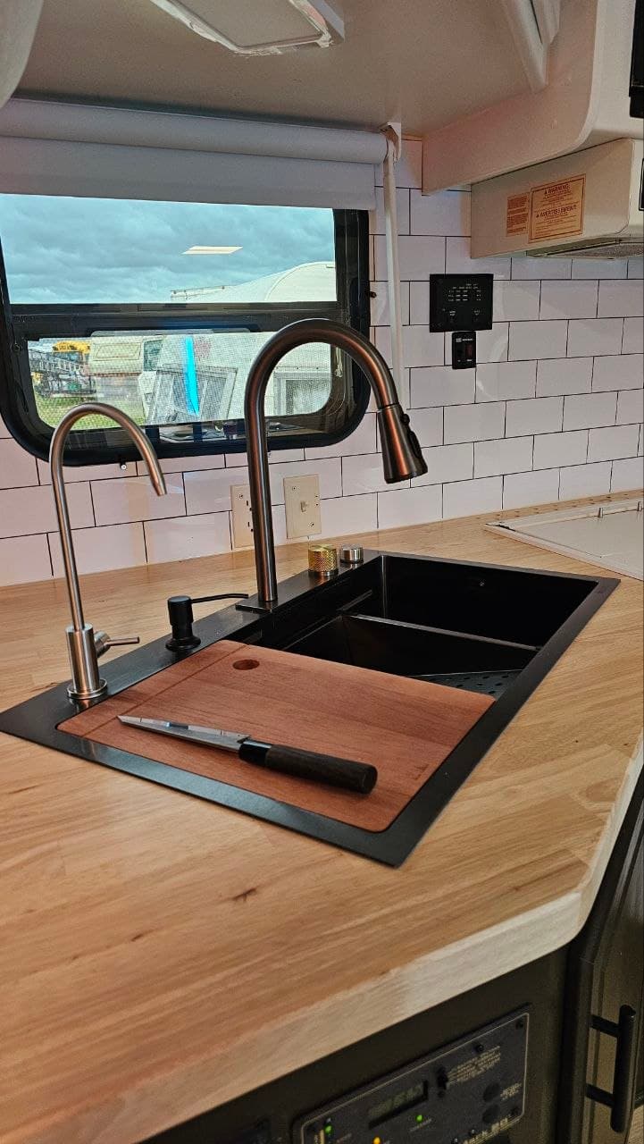 Custom wood countertop, black sink and modern faucet in a renovated trailer