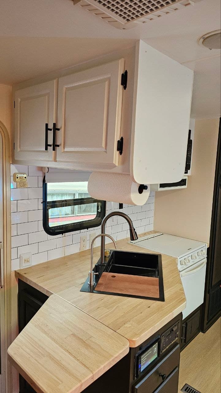 Kitchen after renovation: white refinished cabinets, subway tile backsplash, butcher block counters